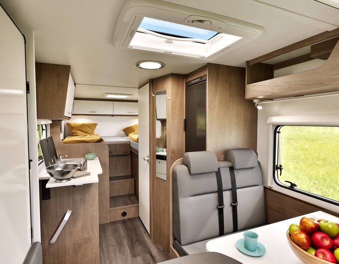 Carado motorhome interior with dinette, kitchen, roof window and single beds in the rear