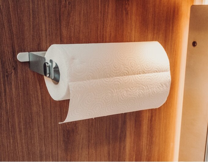 Paper towel roll on a metal holder mounted to a wooden panel in a Carado motorhome