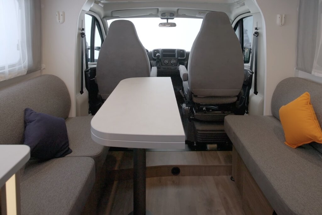 Carado motorhome interior with lounge area, table and view of the cab