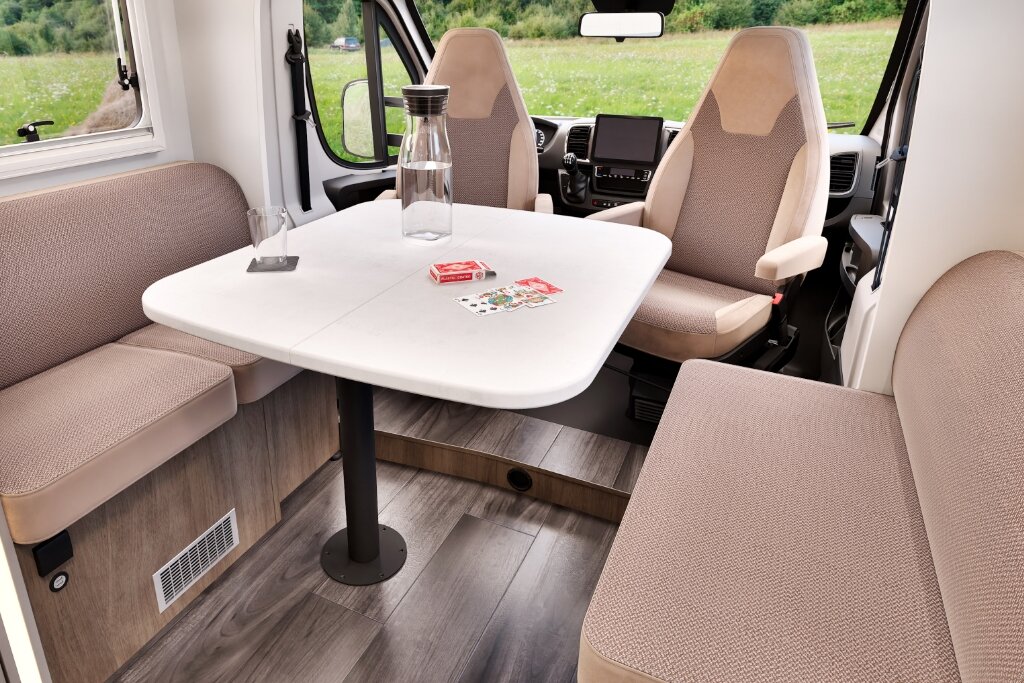 Carado motorhome lounge with table, two lengthwise benches and swivelling cab seats