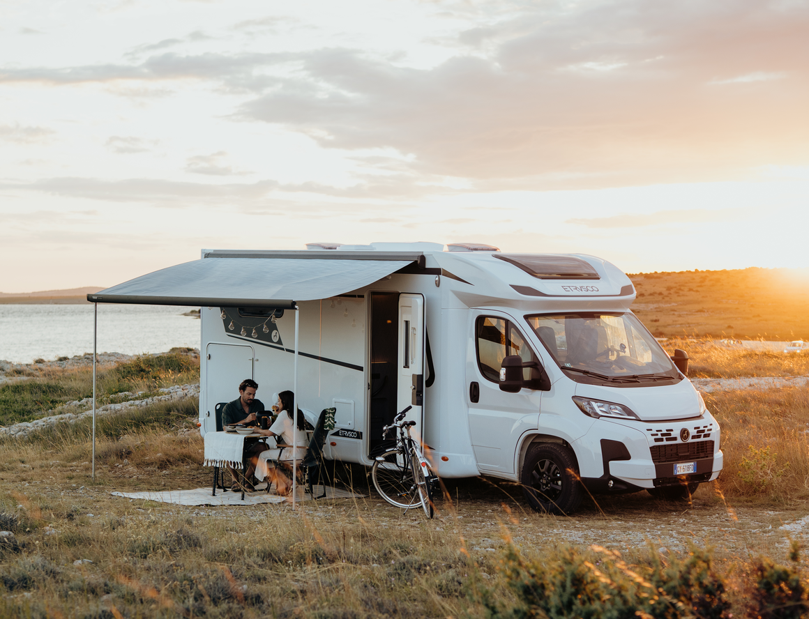 Teilintegriertes Fiat Wohnmobil von Etrusco steht im Hof eines italienischen Hauses, während eine Frau im Sommerkleid aussteigt.