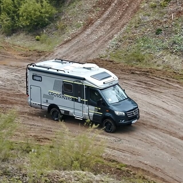 Semi-integrated motorhome seen from the front and above at an angle, driving through an off-road park