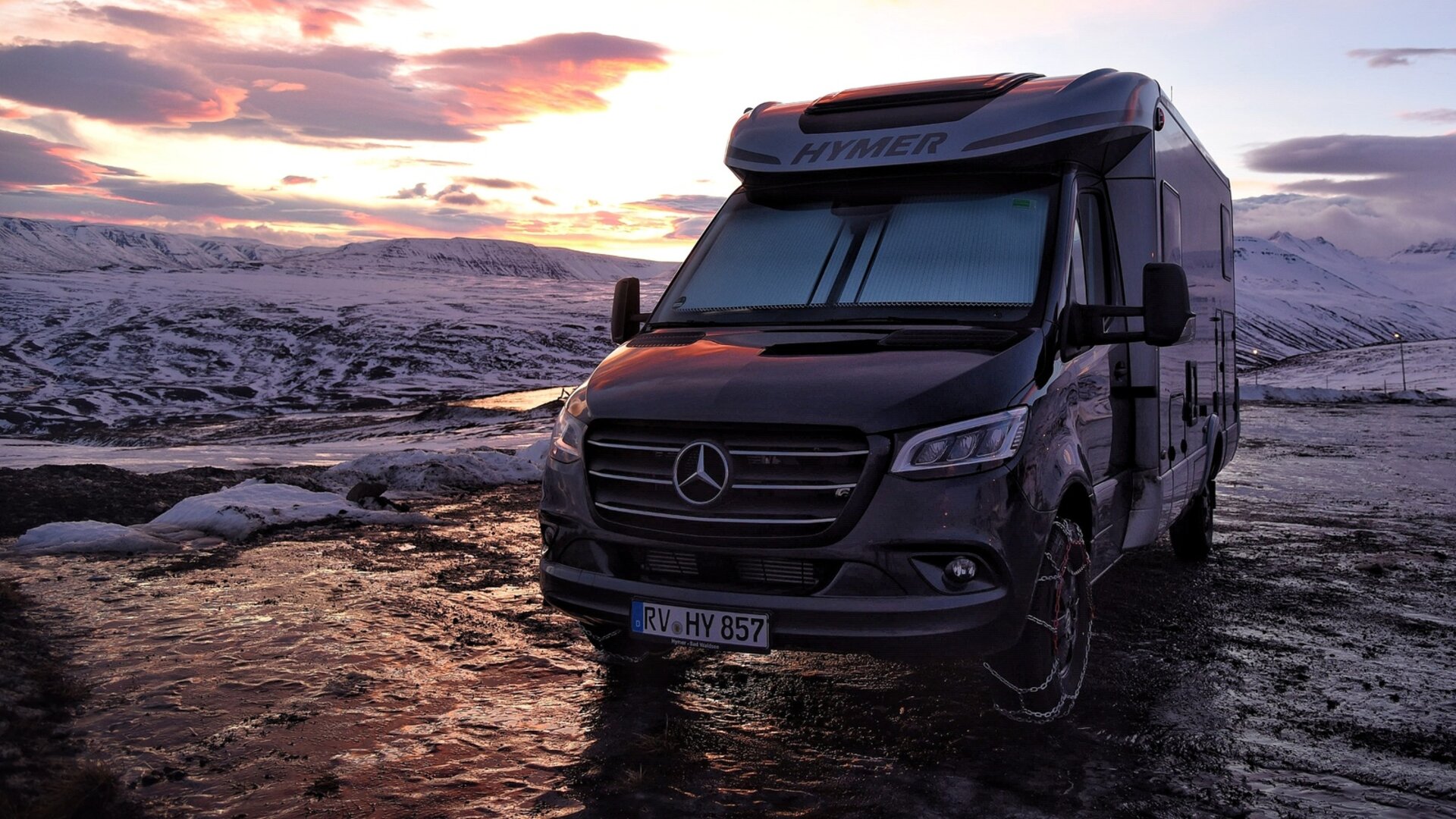 En camper står ved solnedgang i et snødekt område. Fotografert under en rundreise gjennom Island med bobil etter fergeturen.