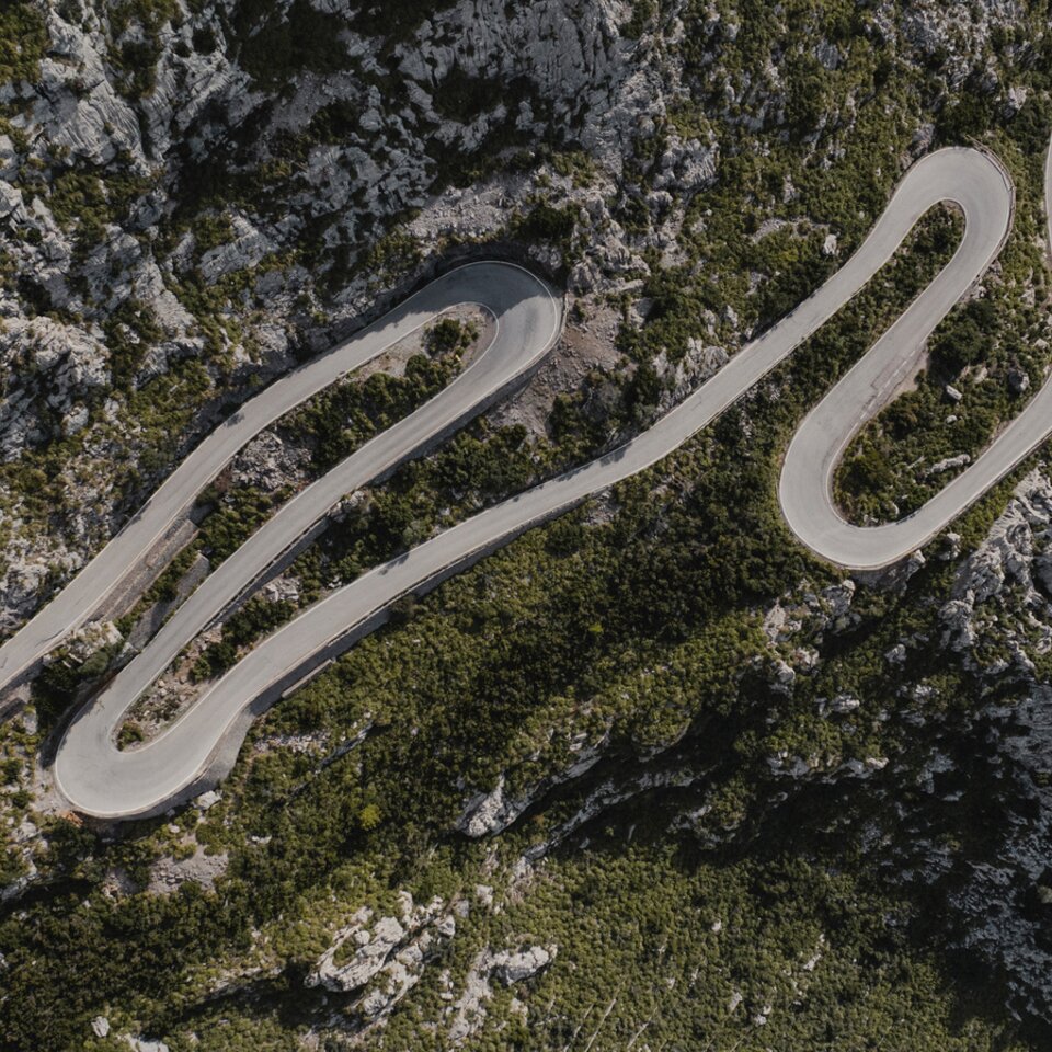 Vue aérienne de routes sinueuses, entourées de rochers et d'arbres.