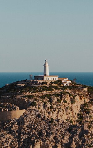 Vue du phare se tenant sur une colline, avec la mer en arrière-plan.