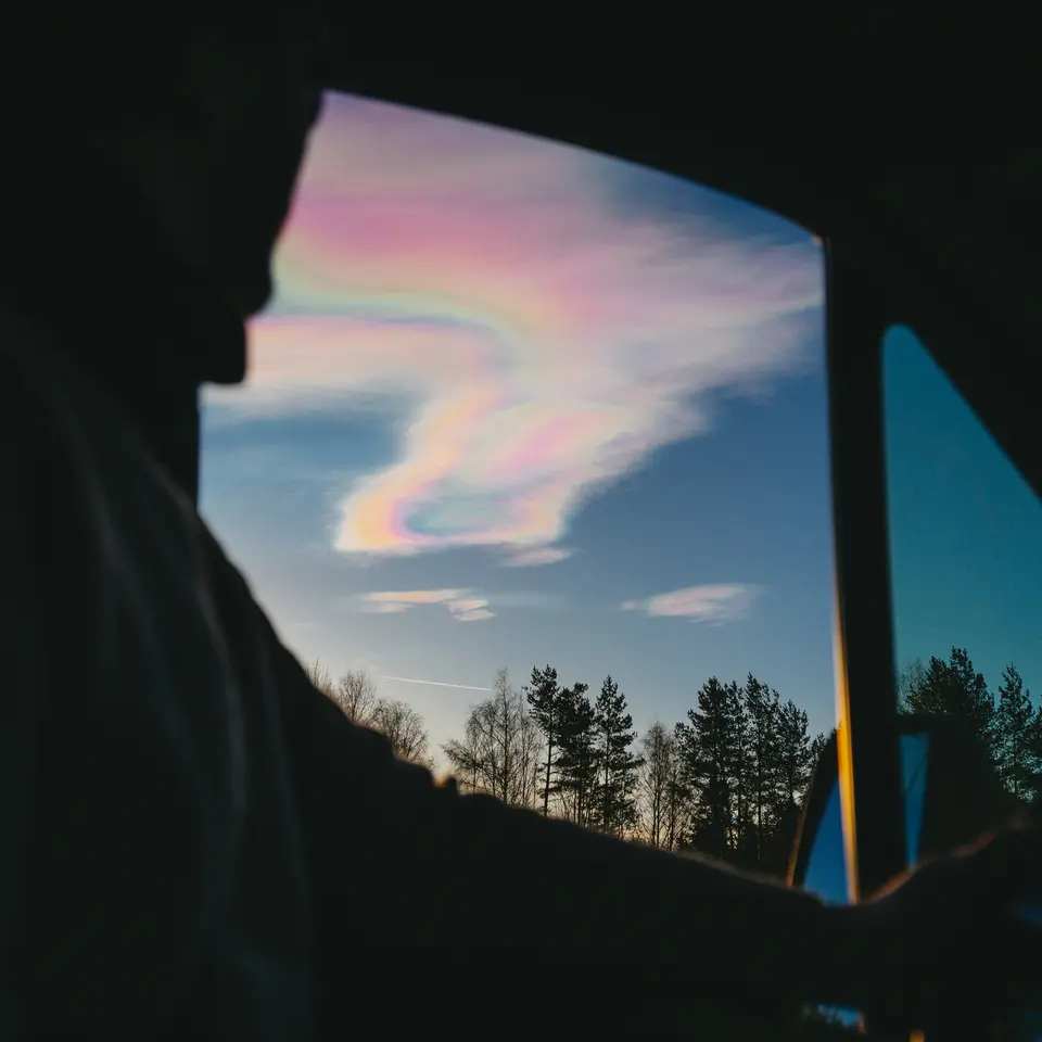 Uitzicht vanuit een camperraam op iriserende wolken